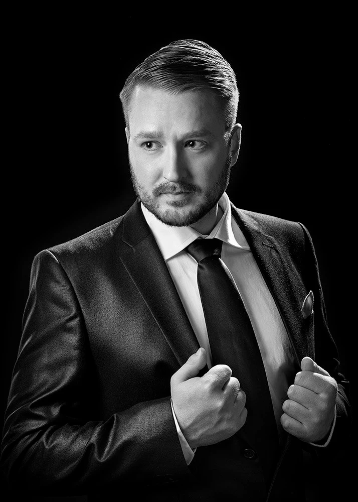 Mustavalkoinen muotokuva miehestä puvussa